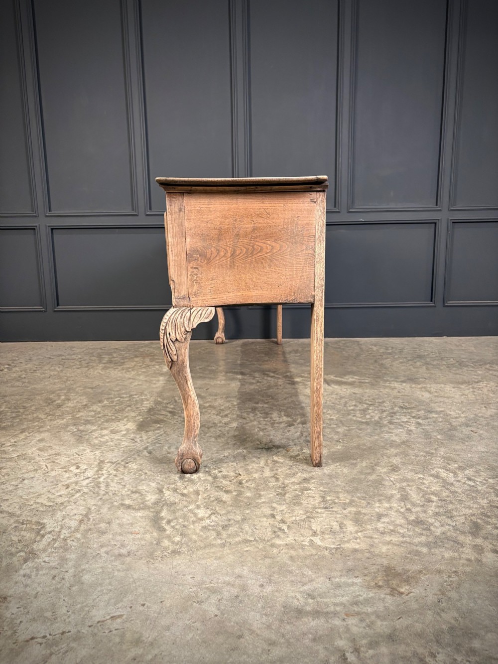 An 18th-century carved oak dresser base with three carved drawer fronts, a decorative apron, cabriole front legs, and claw and ball feet. View IX