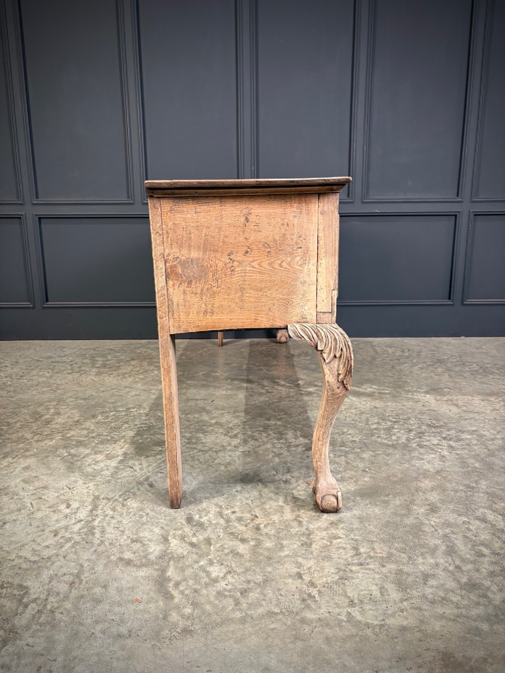 An 18th-century carved oak dresser base with three carved drawer fronts, a decorative apron, cabriole front legs, and claw and ball feet. View XI