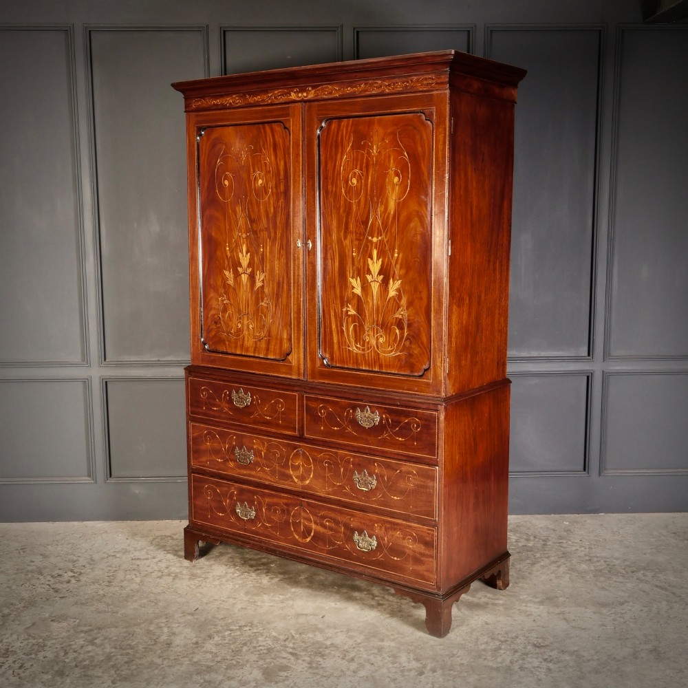 An antique Georgian mahogany gentlemans wardrobe with detailed marquetry inlay on the double doors and lower drawers, standing on bracket feet. View II