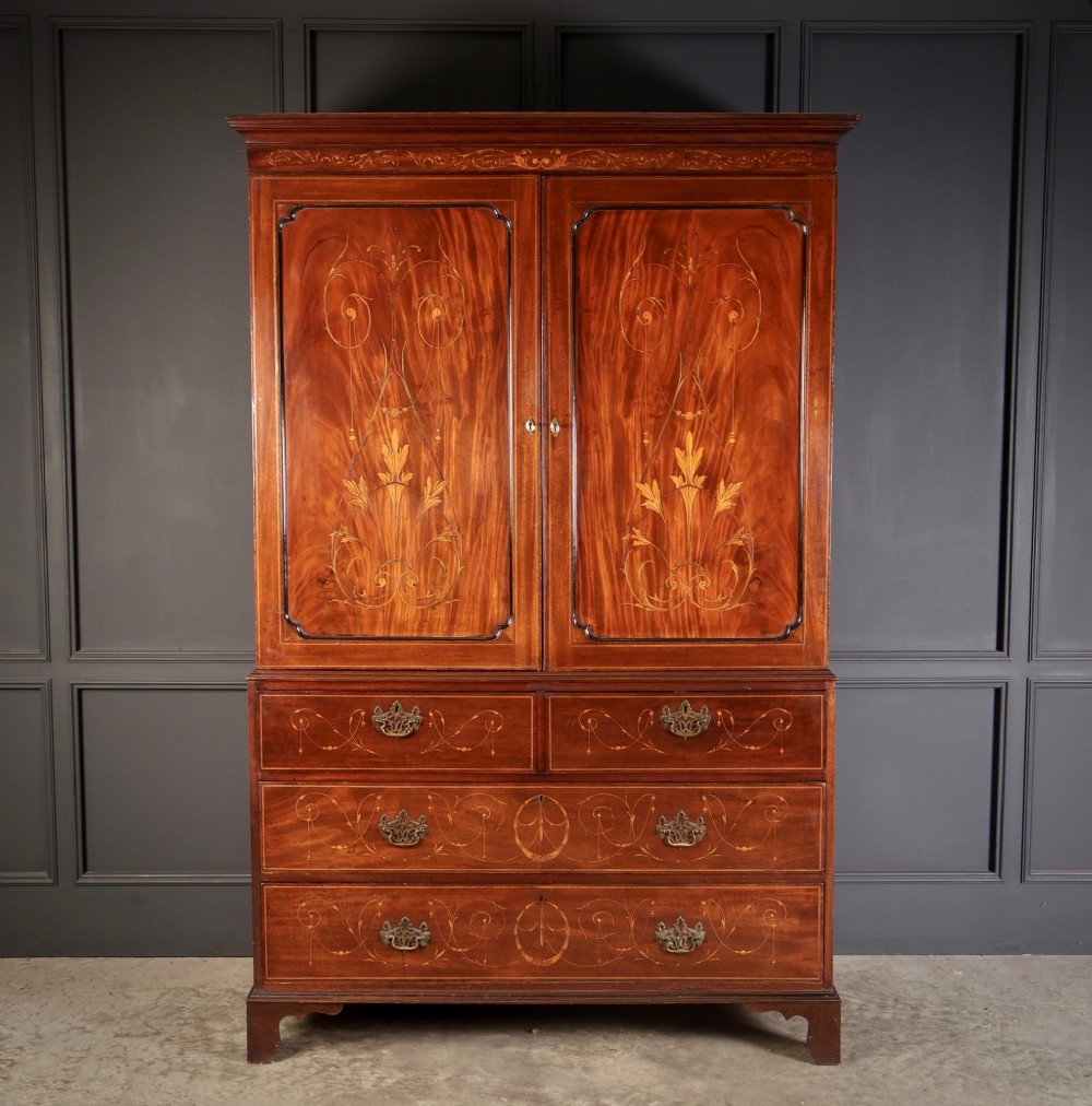 An antique Georgian mahogany gentlemans wardrobe with detailed marquetry inlay on the double doors and lower drawers, standing on bracket feet. View III