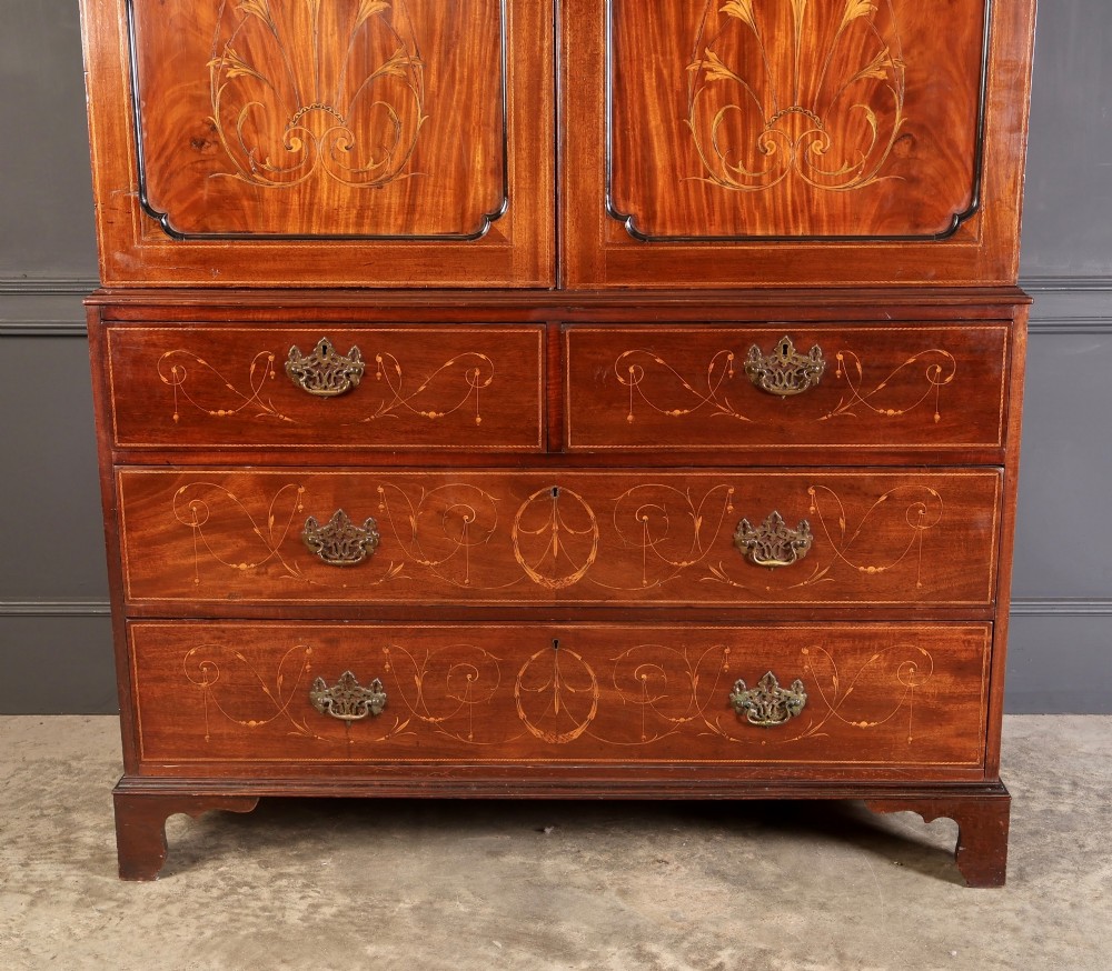 An antique Georgian mahogany gentlemans wardrobe with detailed marquetry inlay on the double doors and lower drawers, standing on bracket feet. View IV