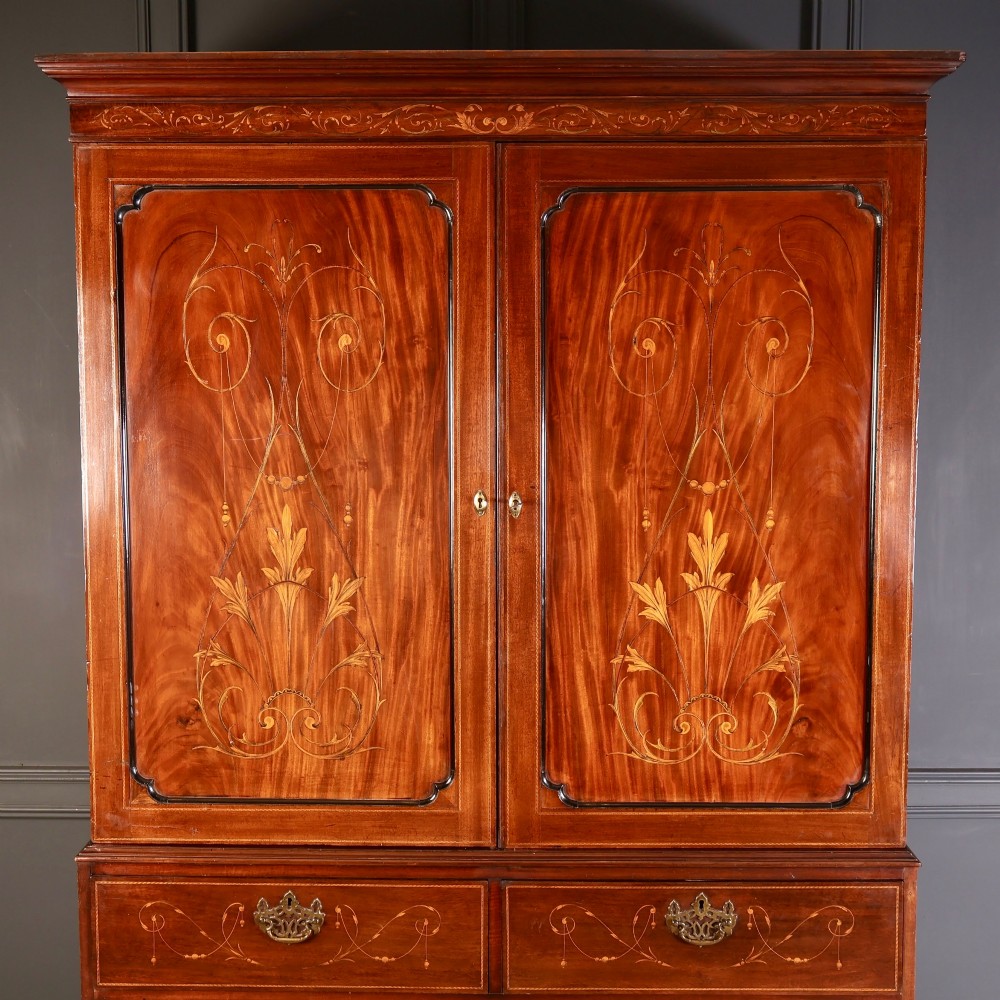 An antique Georgian mahogany gentlemans wardrobe with detailed marquetry inlay on the double doors and lower drawers, standing on bracket feet. View V
