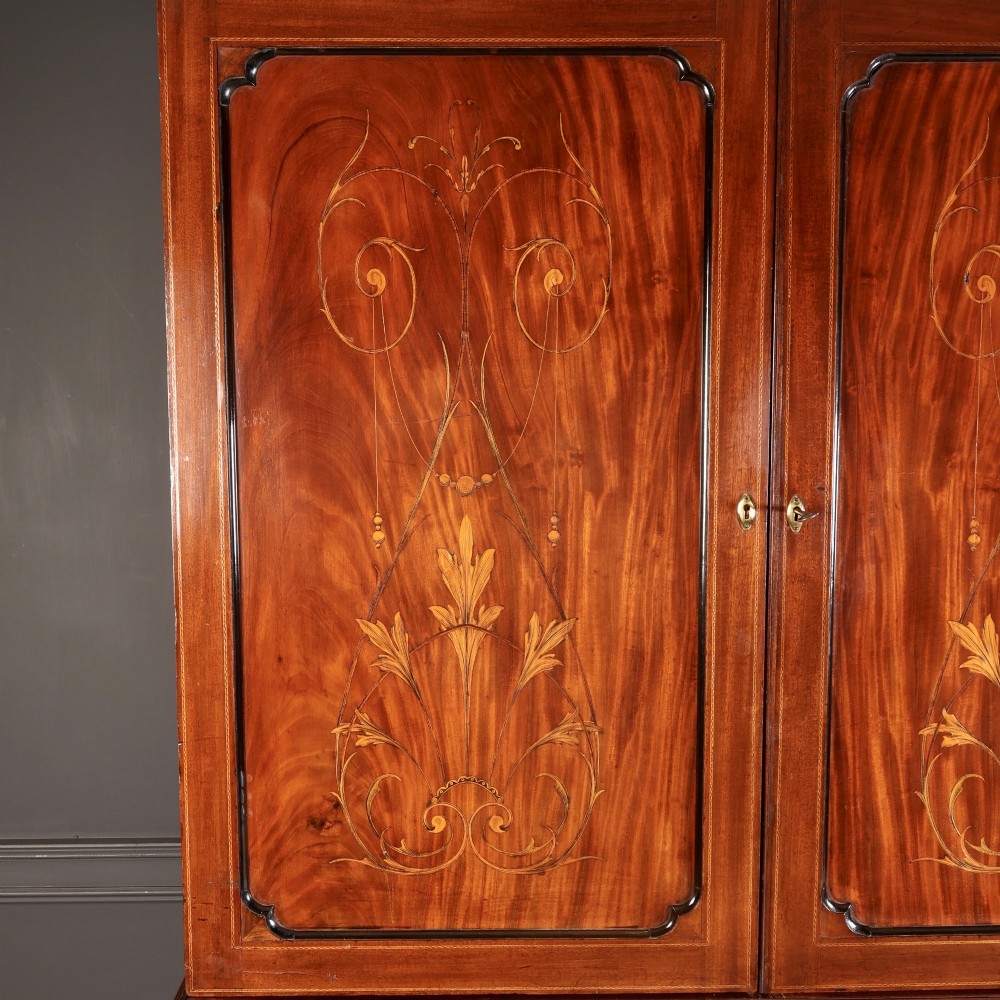 An antique Georgian mahogany gentlemans wardrobe with detailed marquetry inlay on the double doors and lower drawers, standing on bracket feet. View VI