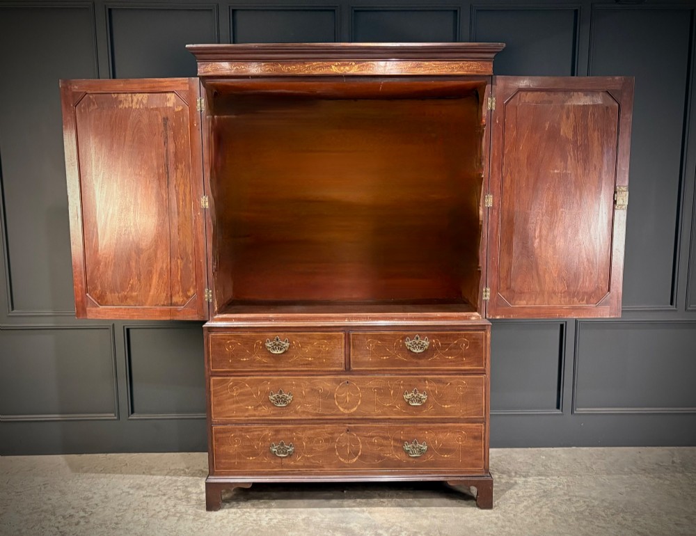 An antique Georgian mahogany gentlemans wardrobe with detailed marquetry inlay on the double doors and lower drawers, standing on bracket feet. View XI