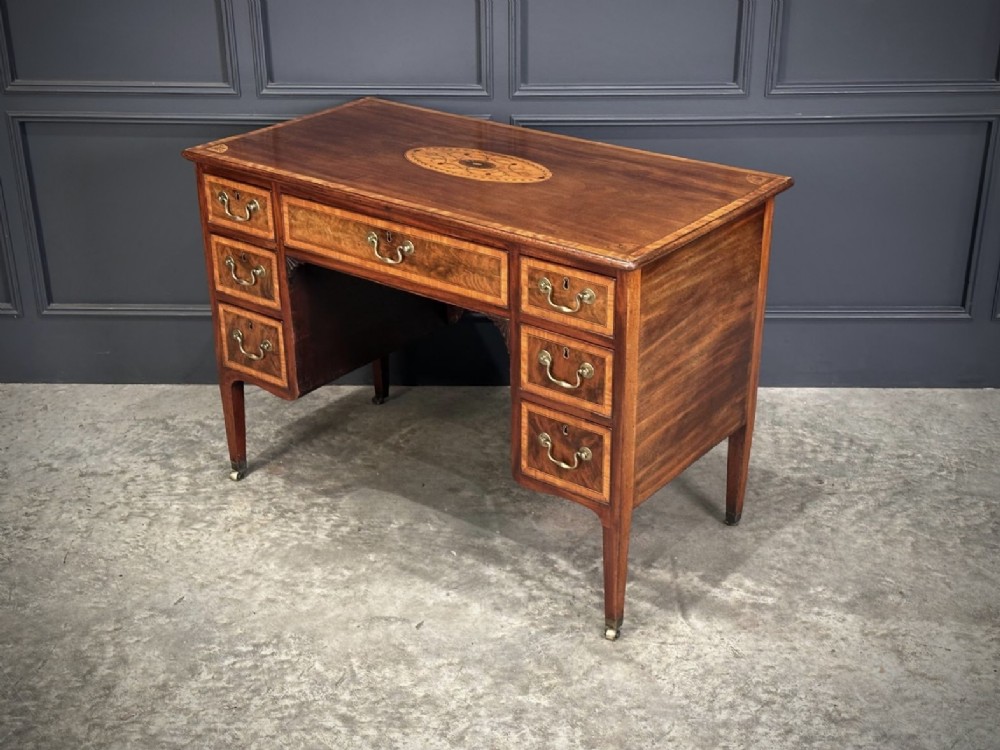 An eighteenth-century mahogany writing desk featuring a central oval floral marquetry inlay on top, crossbanded borders, seven drawers with brass handles, and square tapered legs. View III