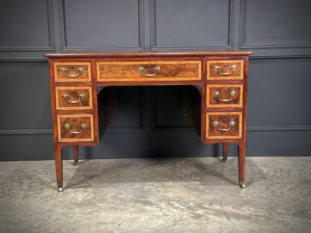 An eighteenth-century mahogany writing desk featuring a central oval floral marquetry inlay on top, crossbanded borders, seven drawers with brass handles, and square tapered legs. View VII