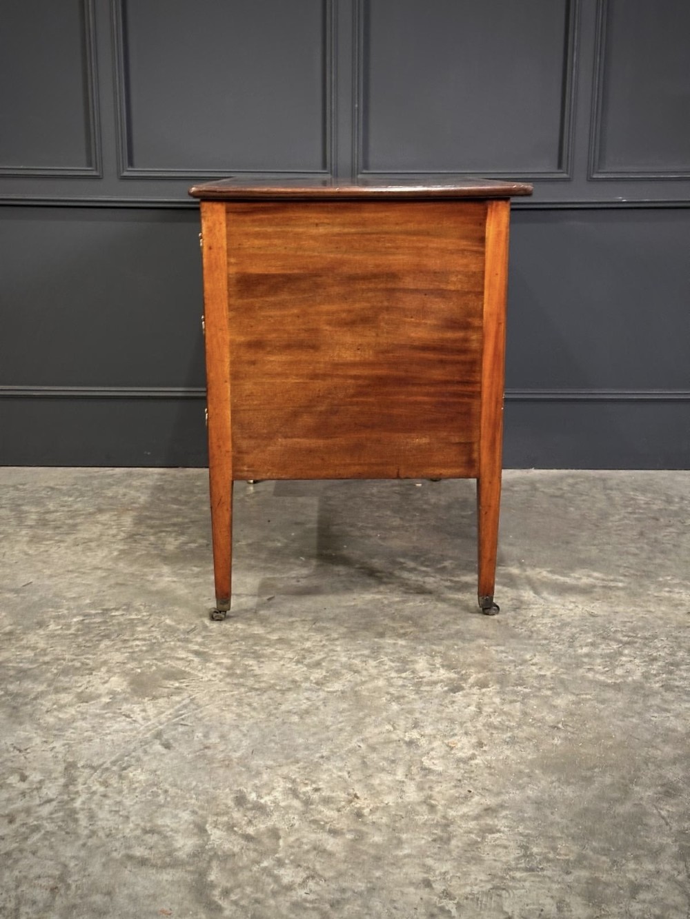 An eighteenth-century mahogany writing desk featuring a central oval floral marquetry inlay on top, crossbanded borders, seven drawers with brass handles, and square tapered legs. View VIII