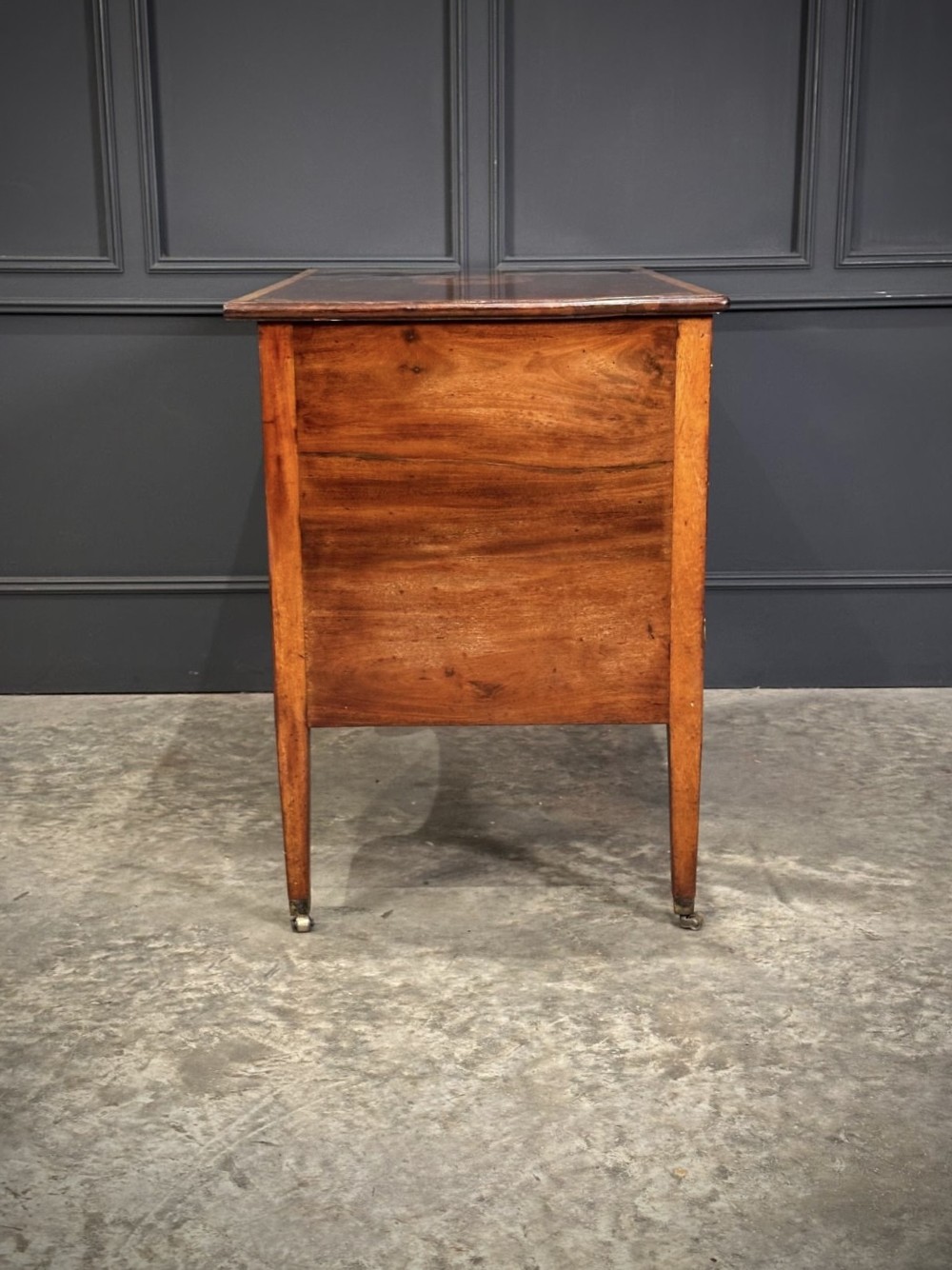 An eighteenth-century mahogany writing desk featuring a central oval floral marquetry inlay on top, crossbanded borders, seven drawers with brass handles, and square tapered legs. View IX
