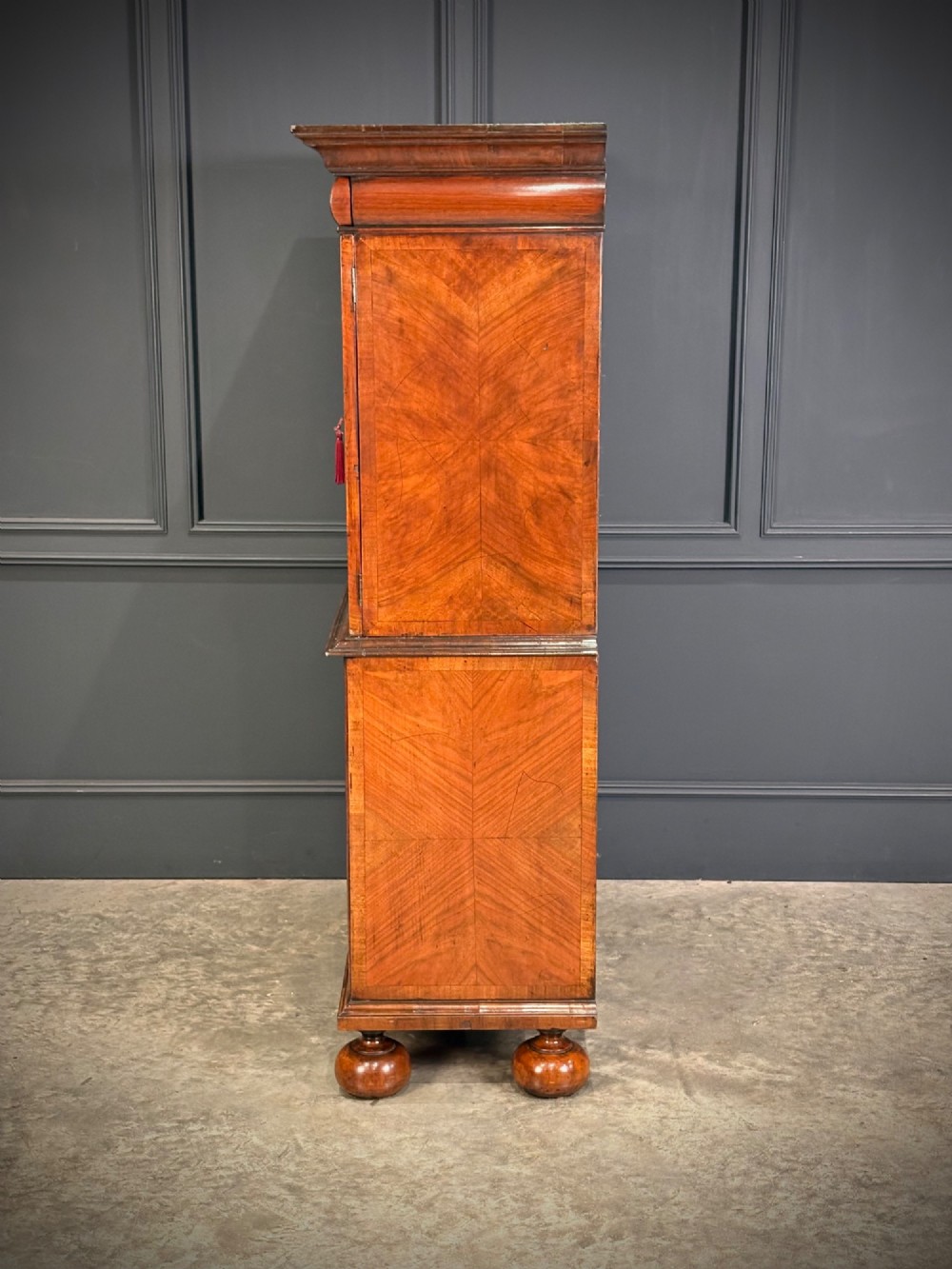 A William and Mary period burr walnut cabinet on stand featuring detailed floral marquetry inlays, teardrop brass handles, and heavy bun feet. View IX