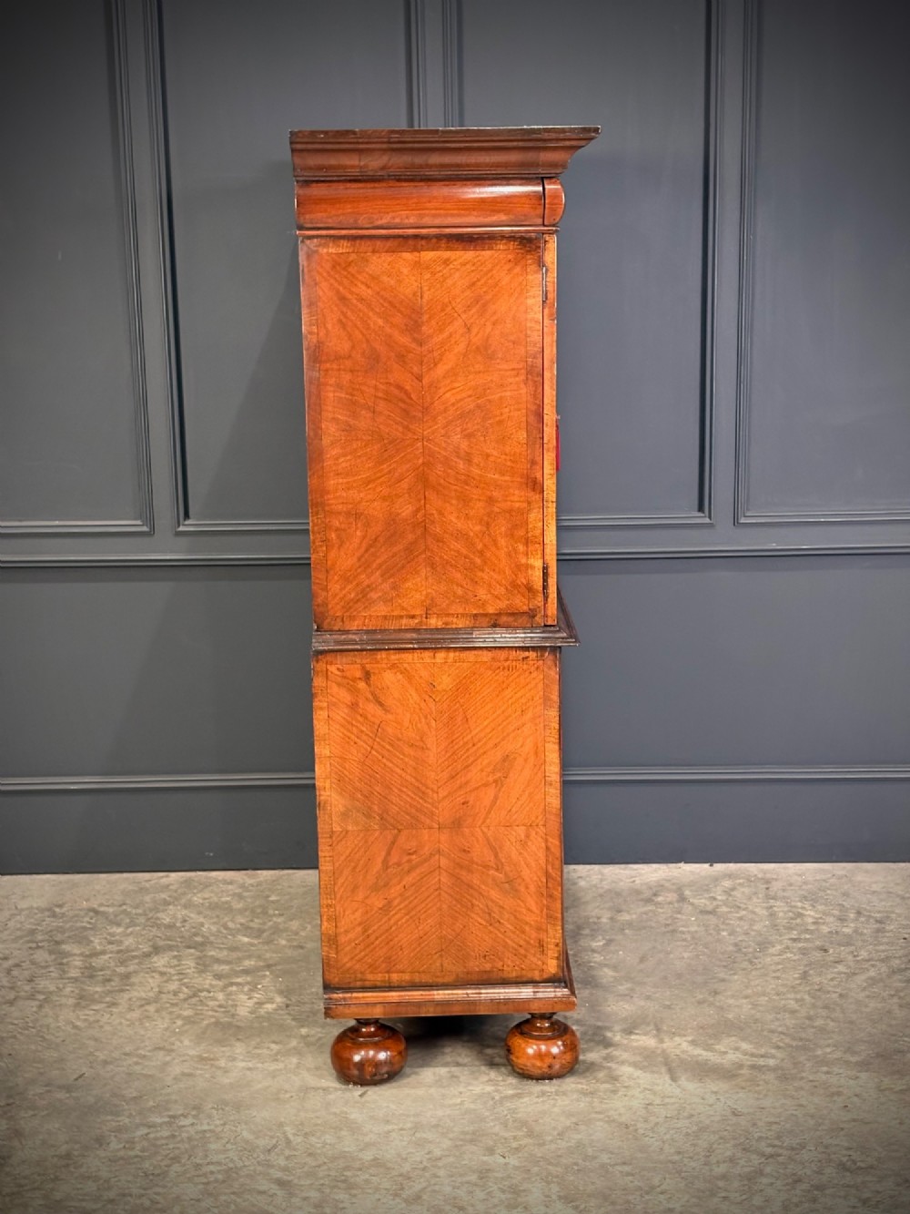 A William and Mary period burr walnut cabinet on stand featuring detailed floral marquetry inlays, teardrop brass handles, and heavy bun feet. View XI