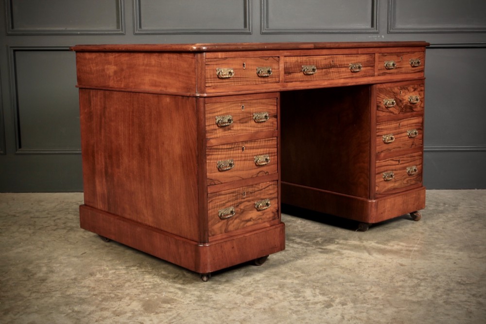 A Victorian walnut pedestal desk featuring a green leather inset top and multiple drawers with brass handles. View II