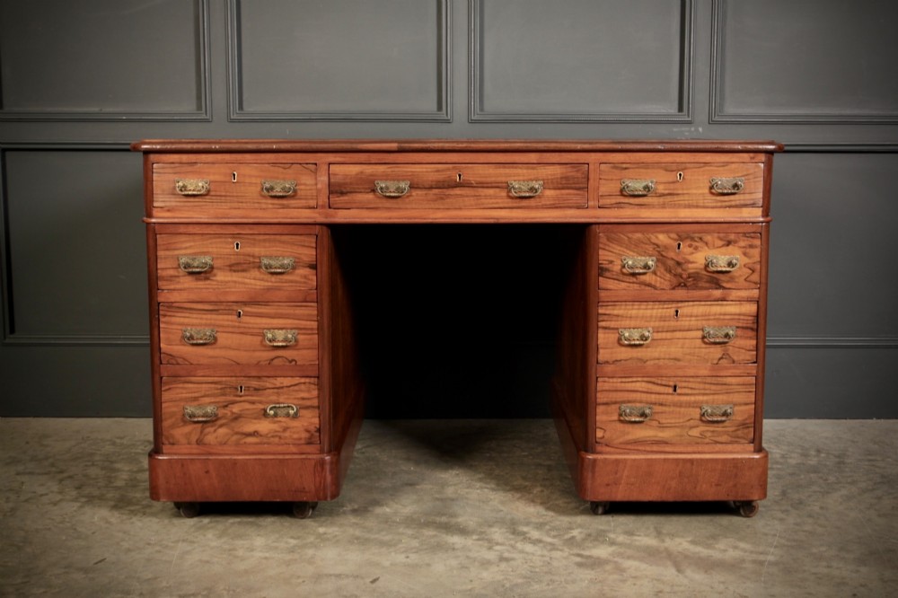 A Victorian walnut pedestal desk featuring a green leather inset top and multiple drawers with brass handles. View IV