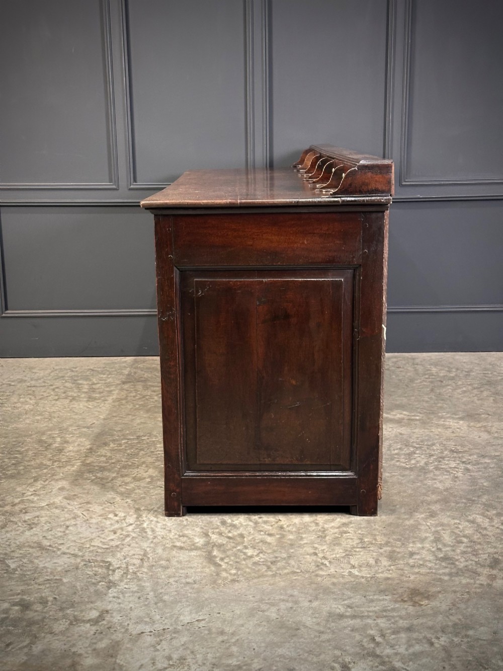 An 18th-century dark oak dresser base featuring three main drawers over three arched cupboard doors with star inlay details and brass handles. View IX