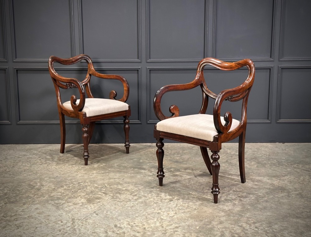 A set of eight Victorian rosewood dining chairs with balloon backs, carved details, scroll armrests, and neutral beige seats. View II