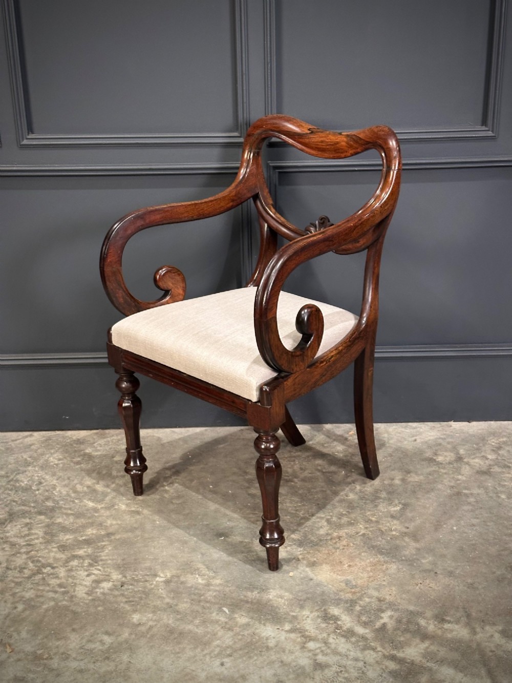 A set of eight Victorian rosewood dining chairs with balloon backs, carved details, scroll armrests, and neutral beige seats. View V
