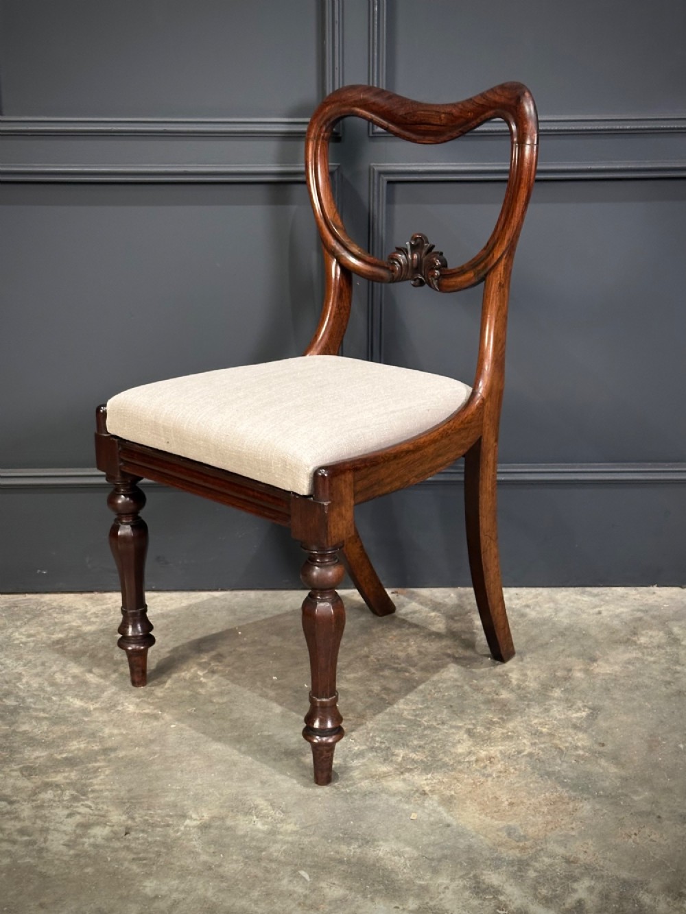 A set of eight Victorian rosewood dining chairs with balloon backs, carved details, scroll armrests, and neutral beige seats. View VII