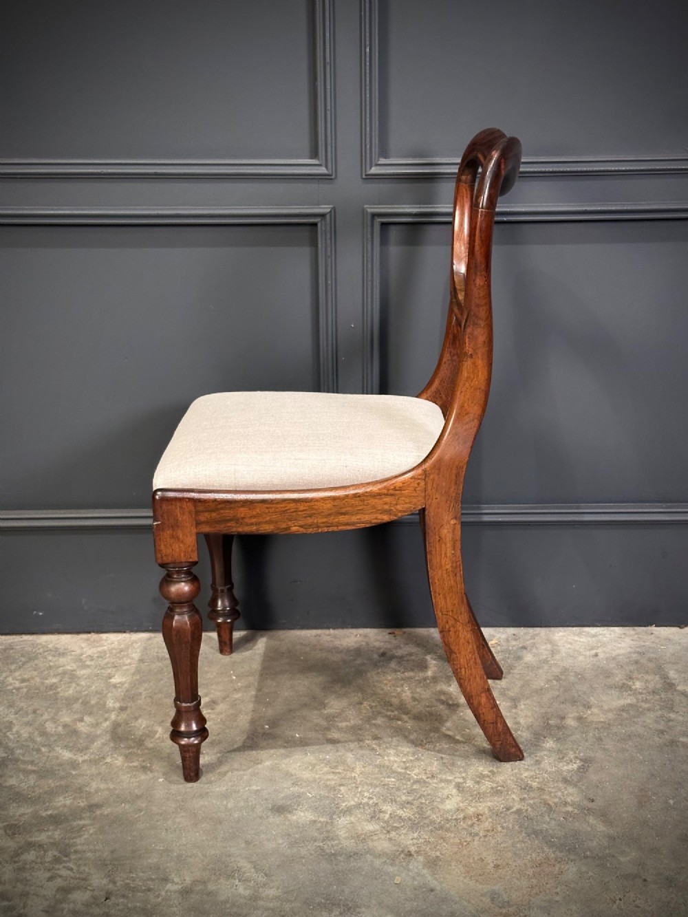 A set of eight Victorian rosewood dining chairs with balloon backs, carved details, scroll armrests, and neutral beige seats. View VIII