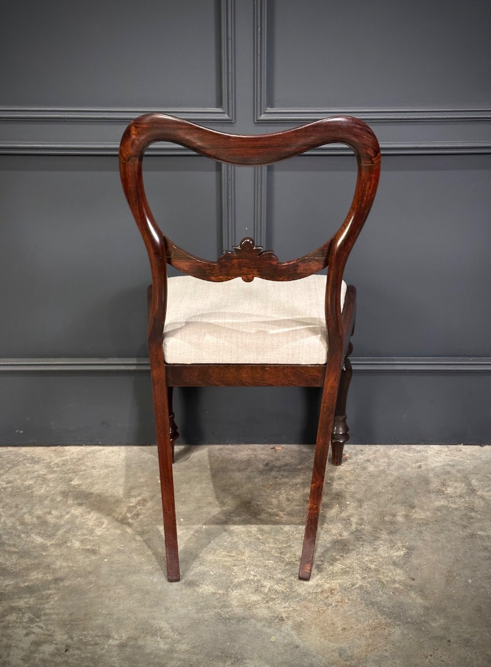 A set of eight Victorian rosewood dining chairs with balloon backs, carved details, scroll armrests, and neutral beige seats. View IX