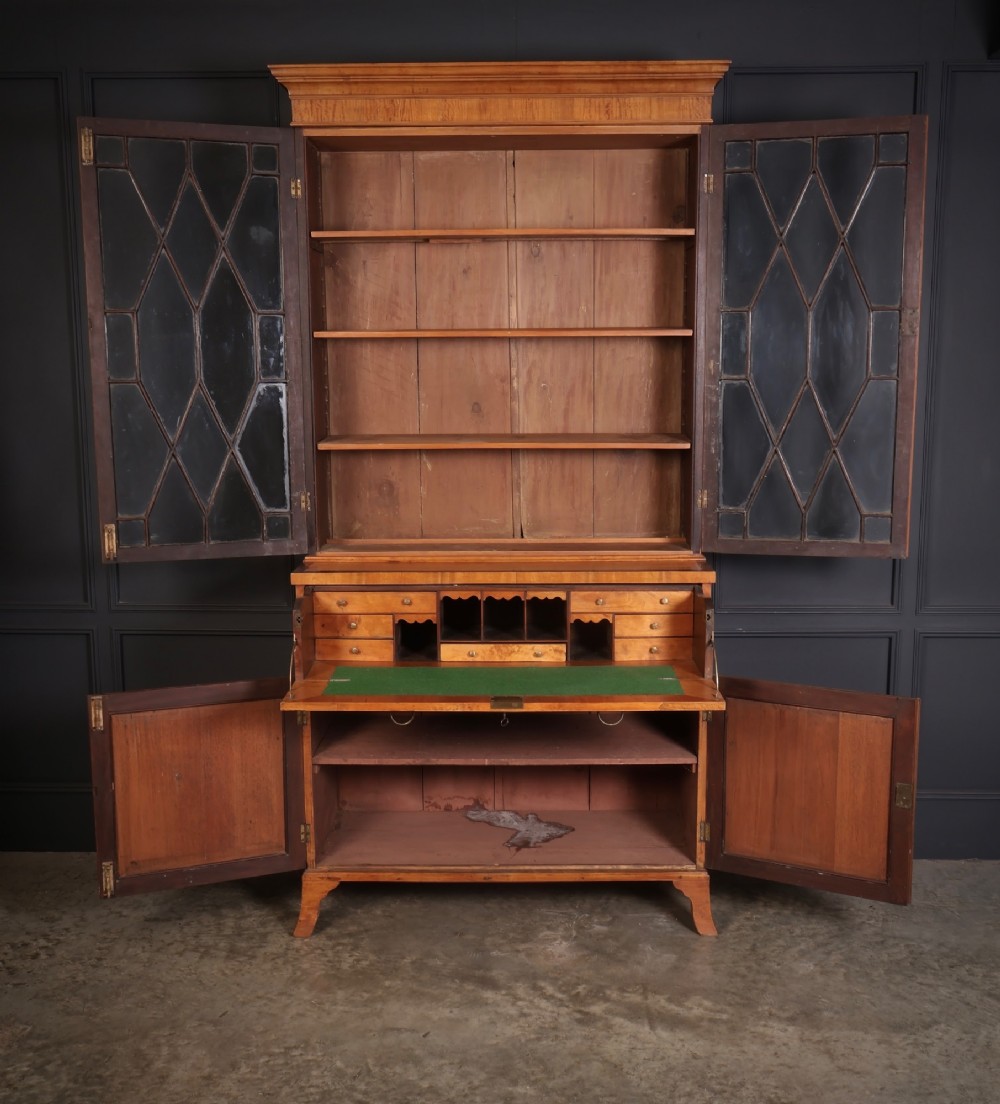 A tall Georgian satinwood secretaire bookcase featuring an upper glazed cabinet with geometric astragal bars, a fold-down desk drawer, and a lower double-door cupboard on splayed bracket feet. View III