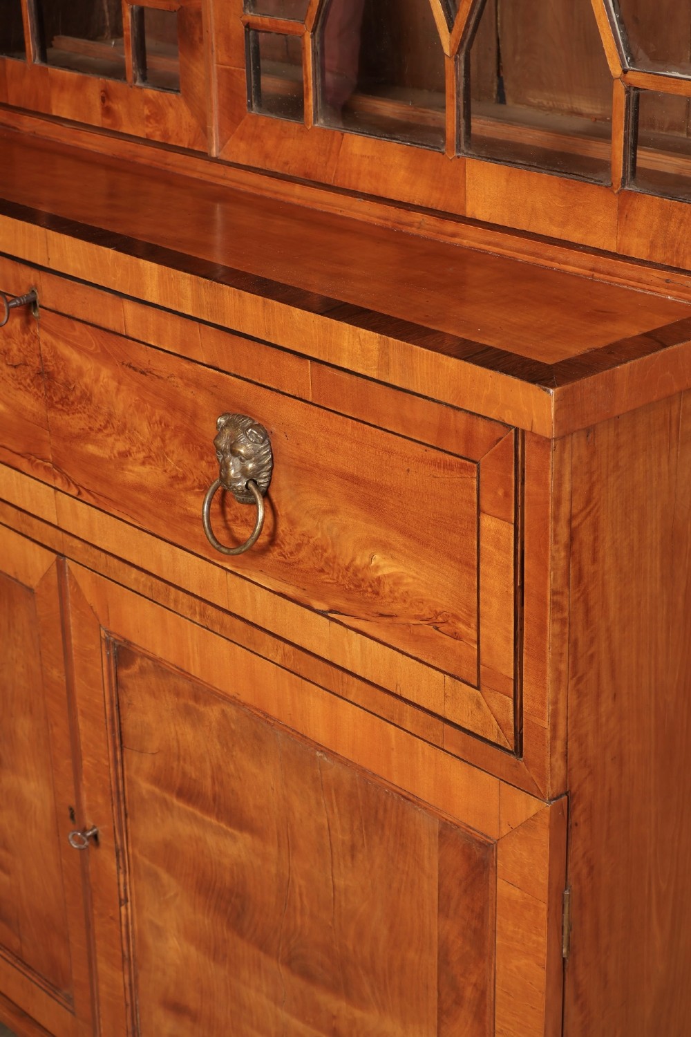 A tall Georgian satinwood secretaire bookcase featuring an upper glazed cabinet with geometric astragal bars, a fold-down desk drawer, and a lower double-door cupboard on splayed bracket feet. View VII