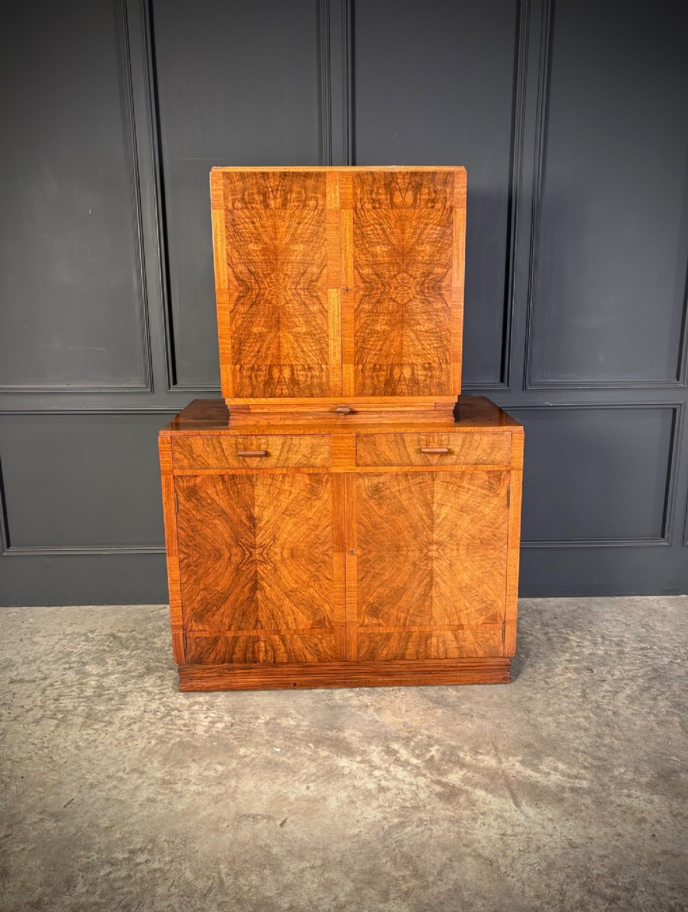 An Art Deco two-tiered cocktail cabinet in figured walnut veneer featuring double doors and geometric paneling. View IV
