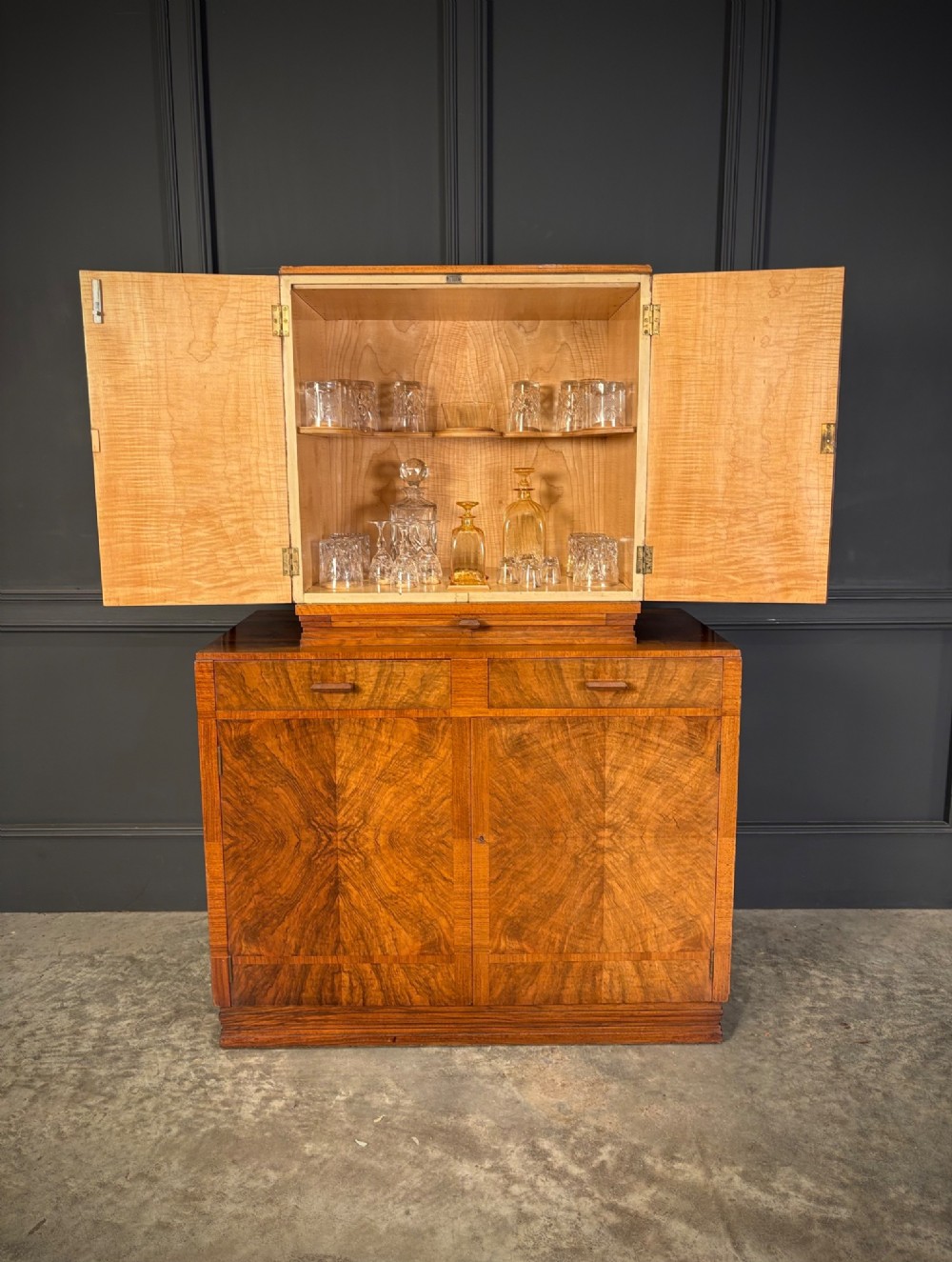 An Art Deco two-tiered cocktail cabinet in figured walnut veneer featuring double doors and geometric paneling. View V