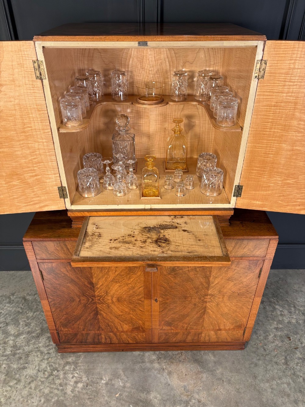 An Art Deco two-tiered cocktail cabinet in figured walnut veneer featuring double doors and geometric paneling. View VII