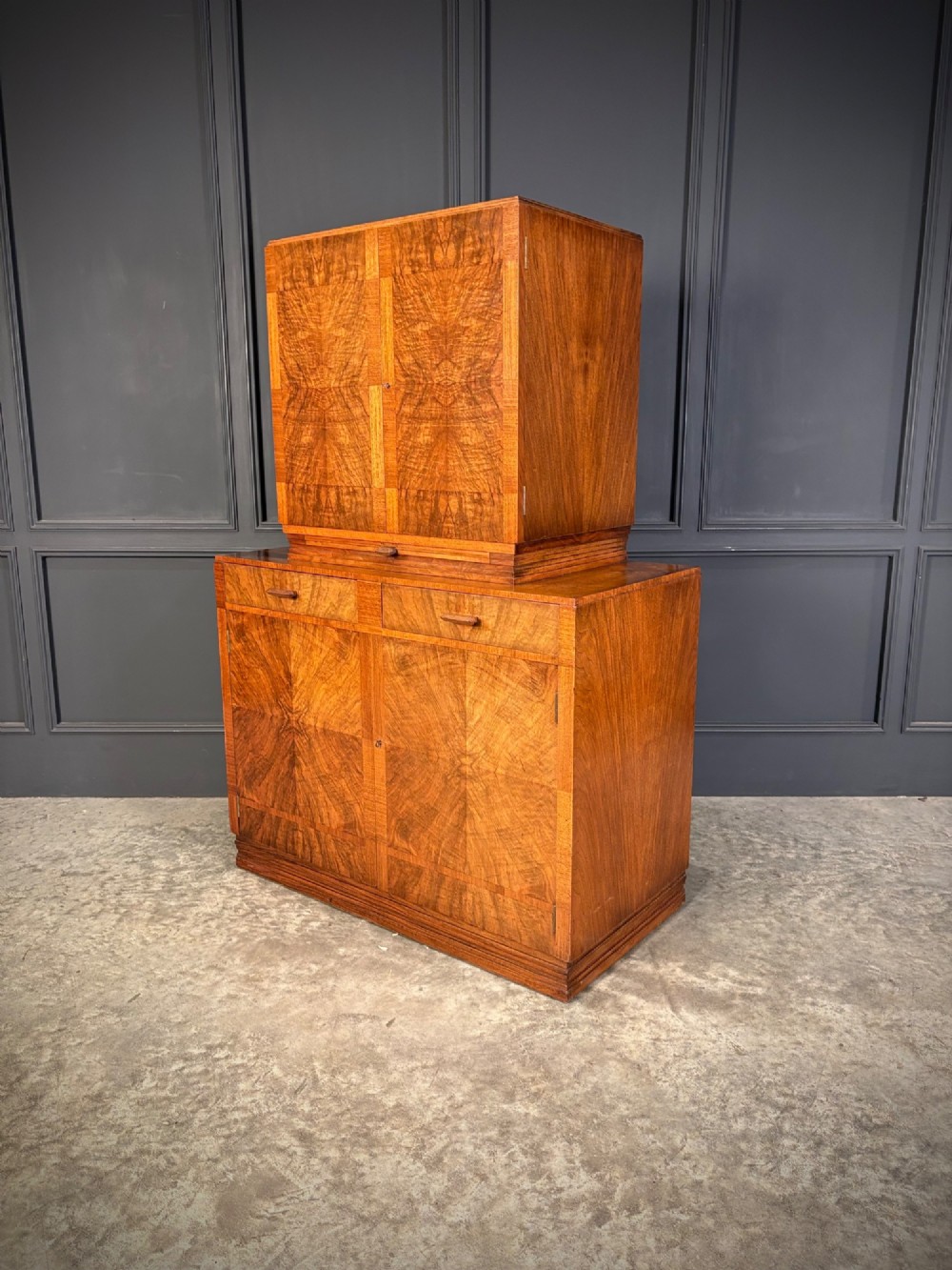 An Art Deco two-tiered cocktail cabinet in figured walnut veneer featuring double doors and geometric paneling. View IX