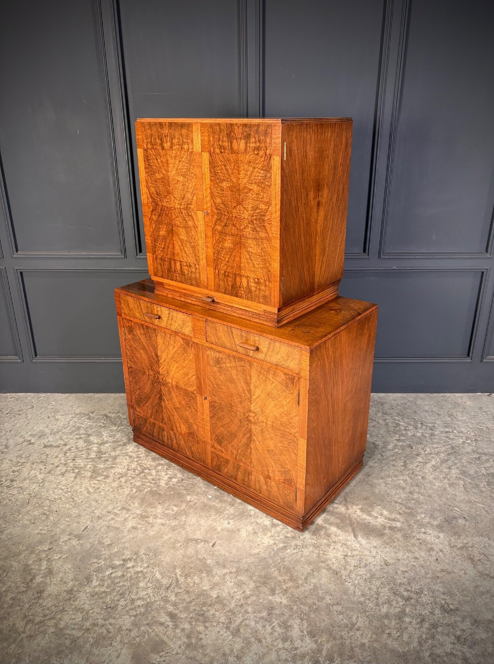An Art Deco two-tiered cocktail cabinet in figured walnut veneer featuring double doors and geometric paneling. View X