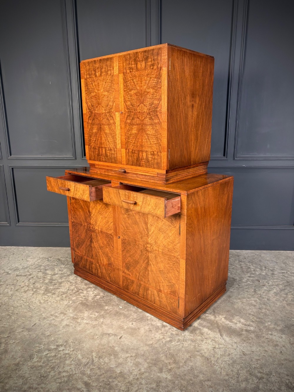 An Art Deco two-tiered cocktail cabinet in figured walnut veneer featuring double doors and geometric paneling. View XI