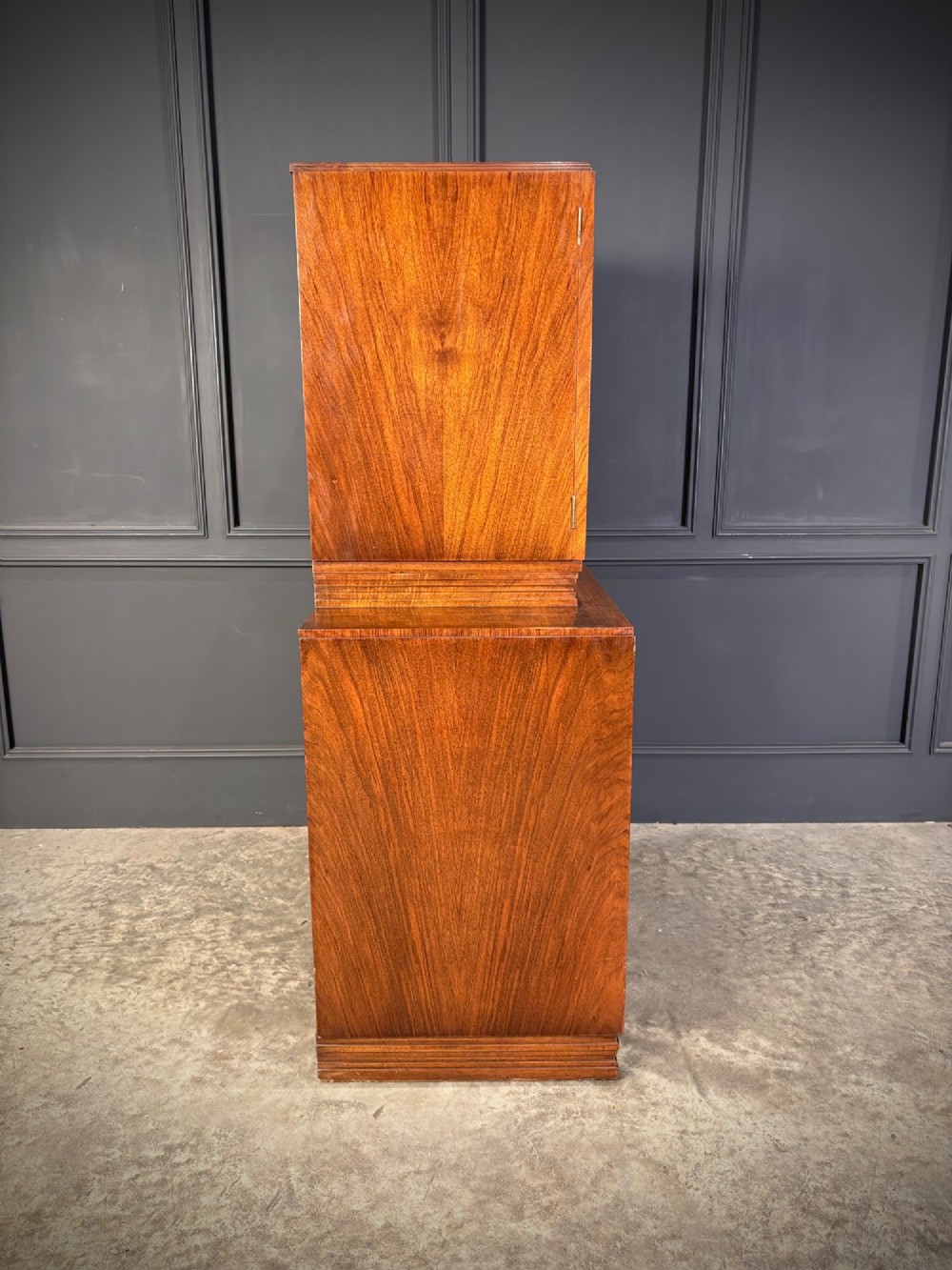 An Art Deco two-tiered cocktail cabinet in figured walnut veneer featuring double doors and geometric paneling. View XIV