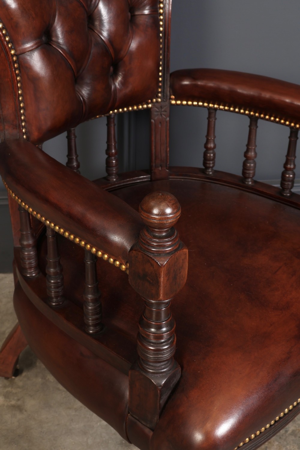 Pair of Victorian mahogany desk chairs with buttoned chestnut brown leather upholstery, brass studding, turned spindles, and castors. View IV