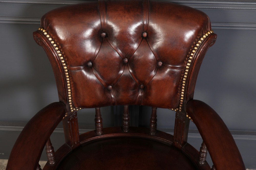 Pair of Victorian mahogany desk chairs with buttoned chestnut brown leather upholstery, brass studding, turned spindles, and castors. View VI