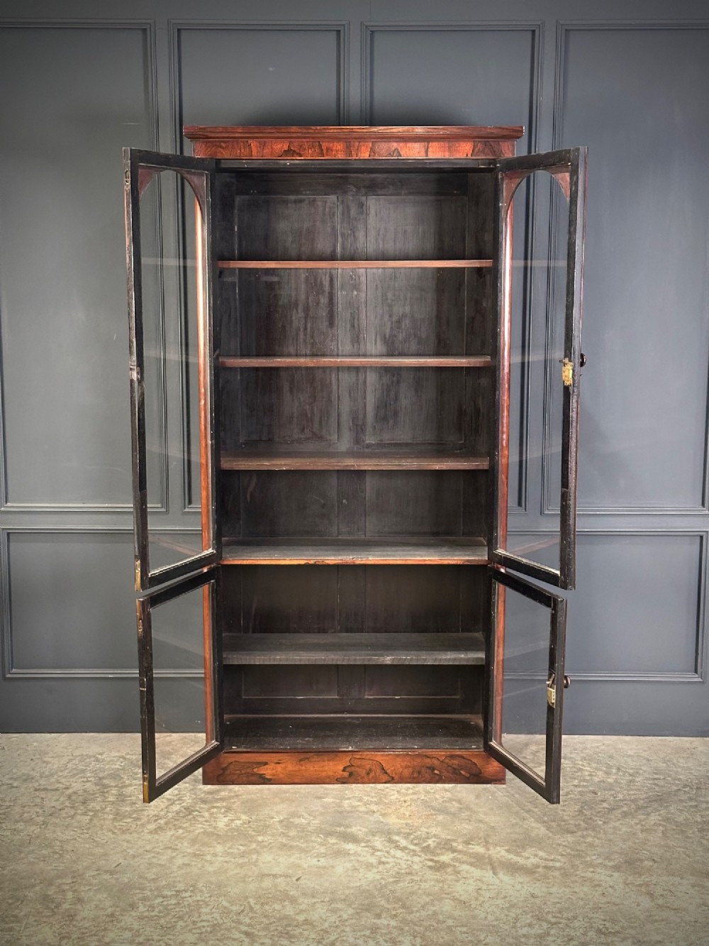 A tall Victorian rosewood bookcase featuring two upper arched glass doors and two lower glass doors on a flat plinth base. View III