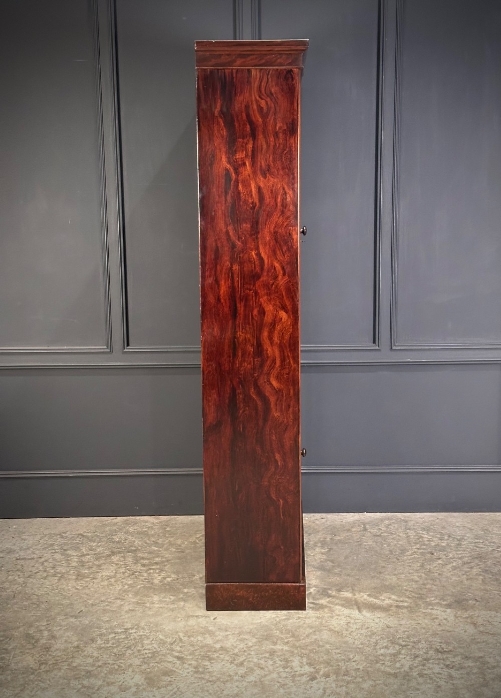 A tall Victorian rosewood bookcase featuring two upper arched glass doors and two lower glass doors on a flat plinth base. View VII
