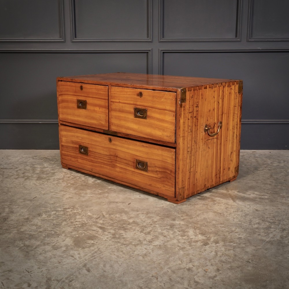 A low rectangular camphor wood campaign chest featuring three drawers with recessed brass handles, brass corner straps, and side carrying handles. View VI