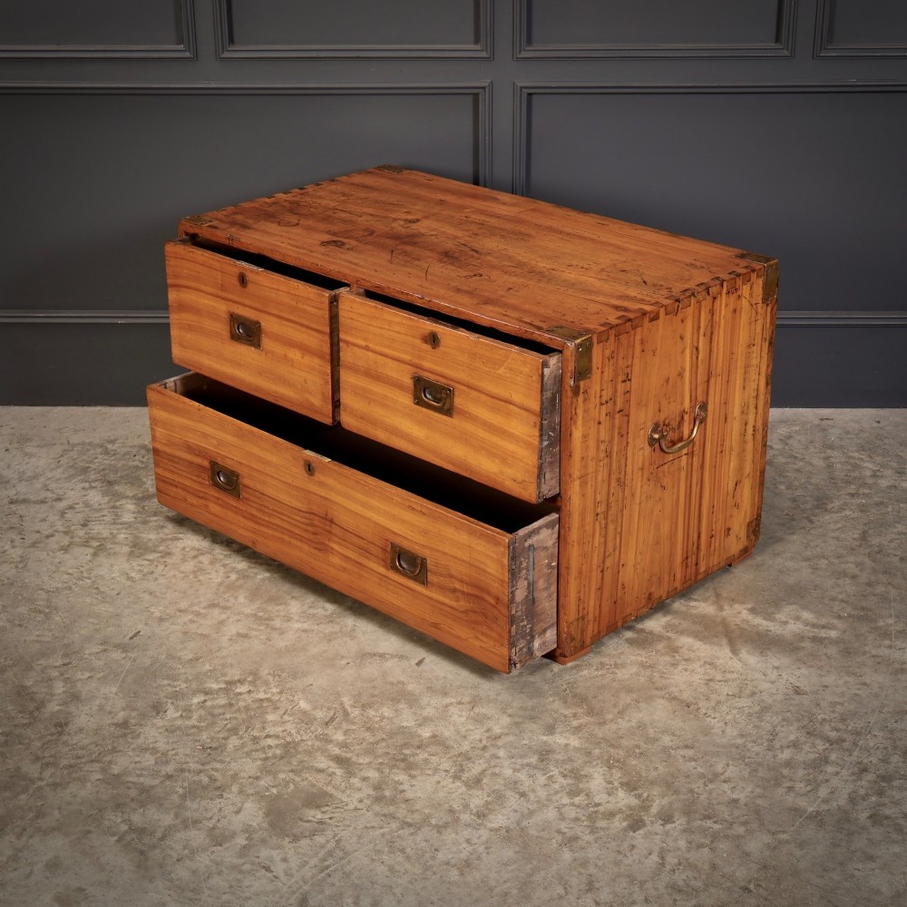 A low rectangular camphor wood campaign chest featuring three drawers with recessed brass handles, brass corner straps, and side carrying handles. View VII