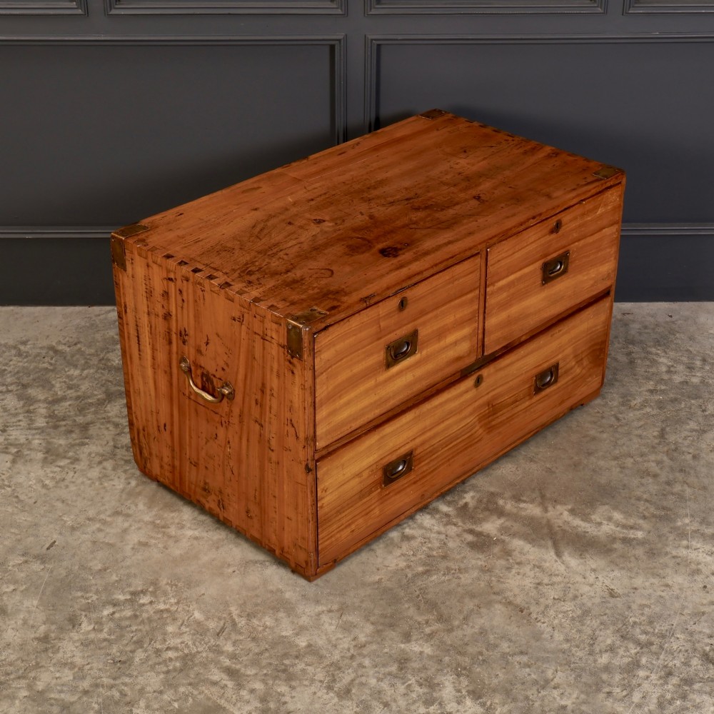 A low rectangular camphor wood campaign chest featuring three drawers with recessed brass handles, brass corner straps, and side carrying handles. View XI
