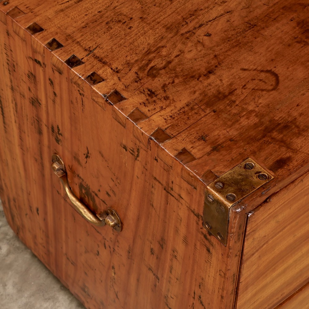 A low rectangular camphor wood campaign chest featuring three drawers with recessed brass handles, brass corner straps, and side carrying handles. View XII