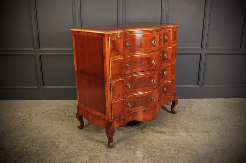 An antique walnut chest of drawers featuring a serpentine curved front, four graduated drawers with brass handles, and carved cabriole legs. View IV