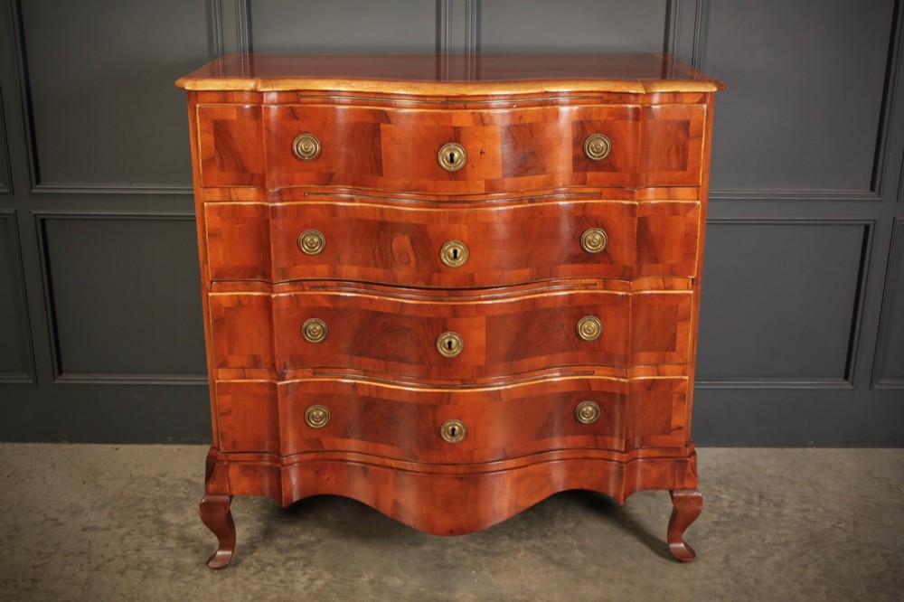 An antique walnut chest of drawers featuring a serpentine curved front, four graduated drawers with brass handles, and carved cabriole legs. View VI