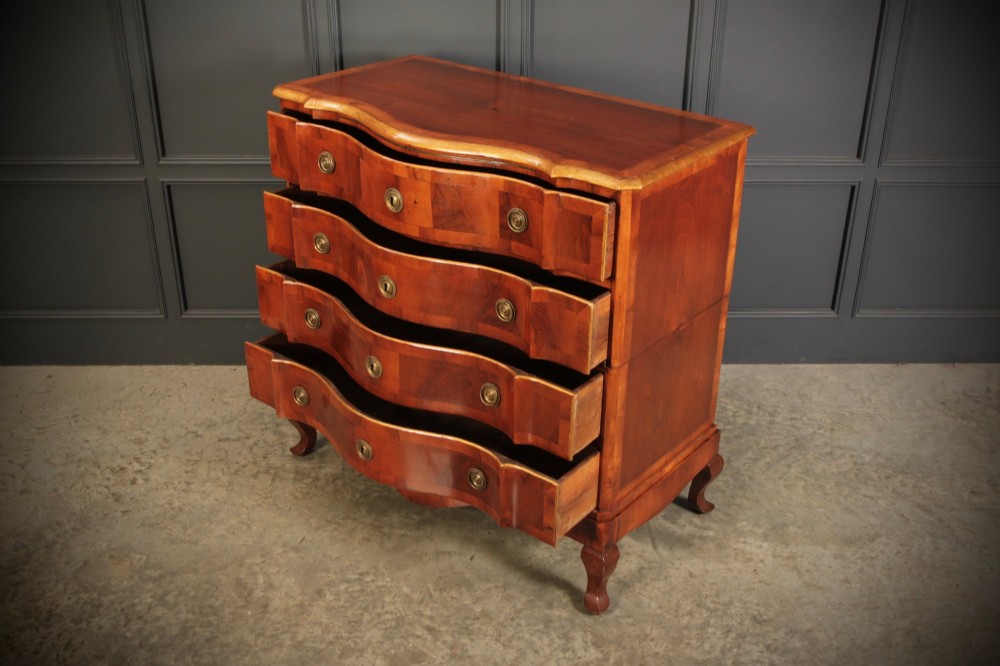 An antique walnut chest of drawers featuring a serpentine curved front, four graduated drawers with brass handles, and carved cabriole legs. View VIII