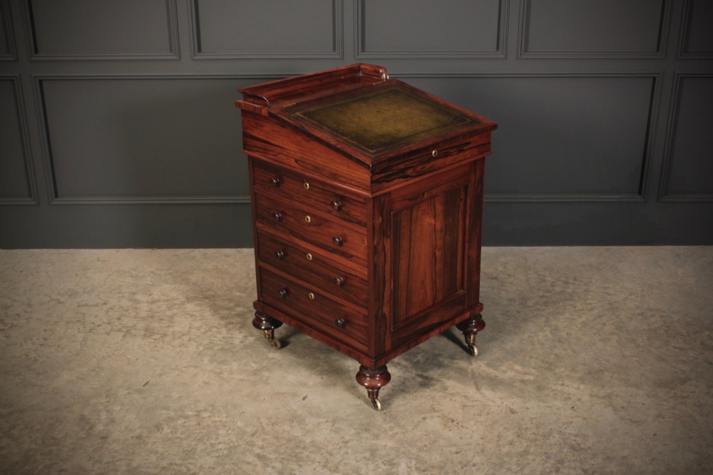 A William IV rosewood Davenport desk featuring a sloped leather writing surface, side drawers with turned knobs, and turned feet on castors. View II