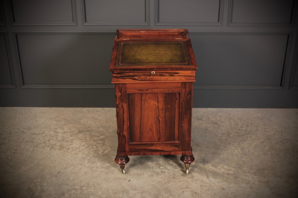 A William IV rosewood Davenport desk featuring a sloped leather writing surface, side drawers with turned knobs, and turned feet on castors. View VI