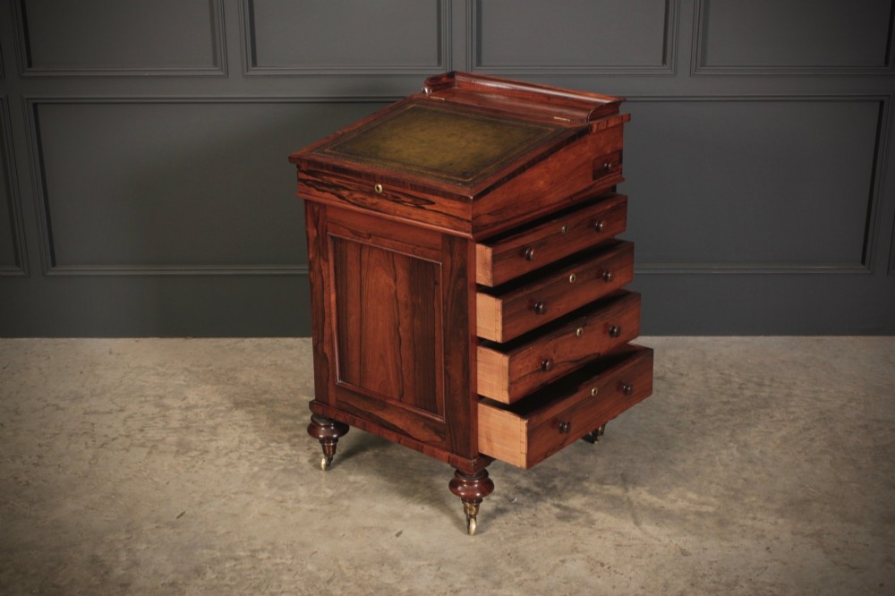 A William IV rosewood Davenport desk featuring a sloped leather writing surface, side drawers with turned knobs, and turned feet on castors. View IX