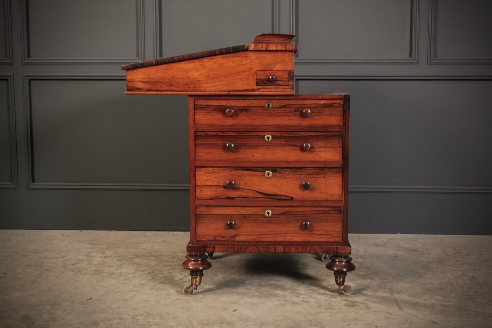 A William IV rosewood Davenport desk featuring a sloped leather writing surface, side drawers with turned knobs, and turned feet on castors. View XI