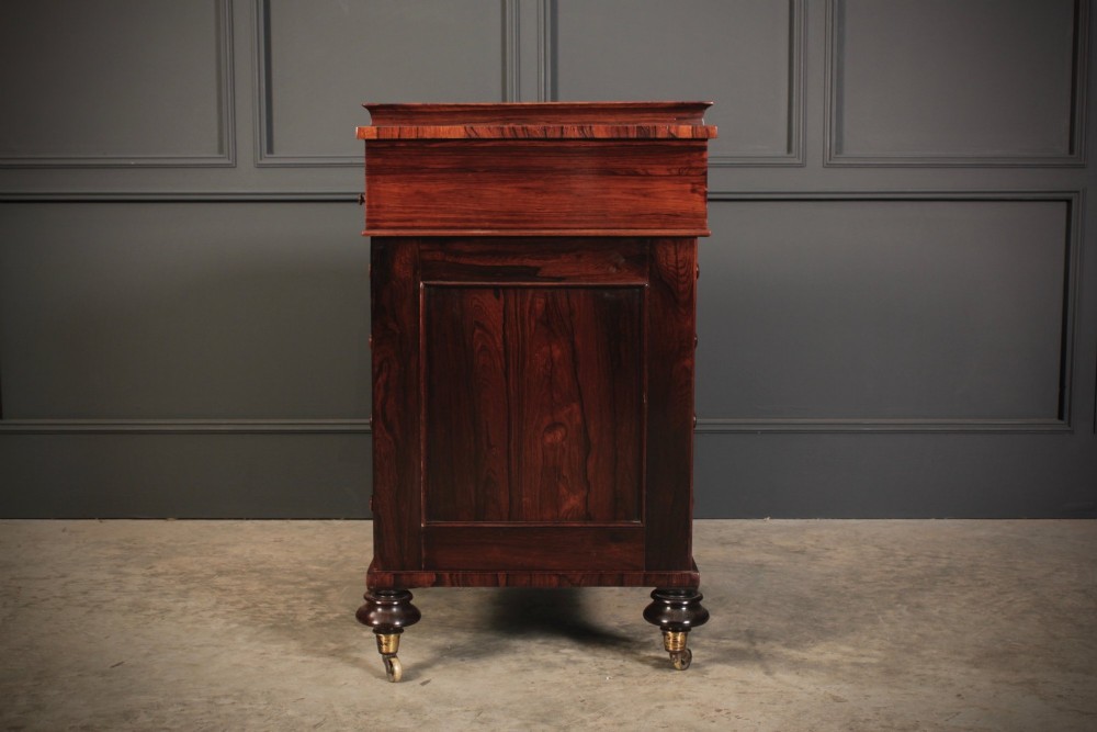 A William IV rosewood Davenport desk featuring a sloped leather writing surface, side drawers with turned knobs, and turned feet on castors. View XII
