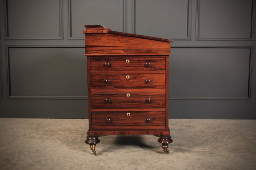A William IV rosewood Davenport desk featuring a sloped leather writing surface, side drawers with turned knobs, and turned feet on castors. View XIII
