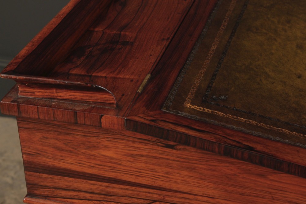 A William IV rosewood Davenport desk featuring a sloped leather writing surface, side drawers with turned knobs, and turned feet on castors. View XIV