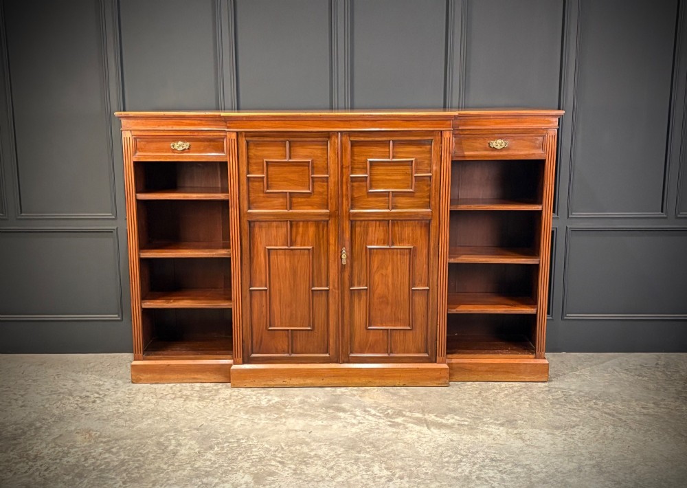 An antique Edwardian walnut breakfront bookcase with a central section featuring geometric panelled doors flanked by open adjustable shelving. View III